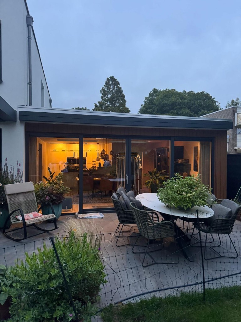 Uitbouw met grote glaspartijen en sfeervolle avondverlichting
