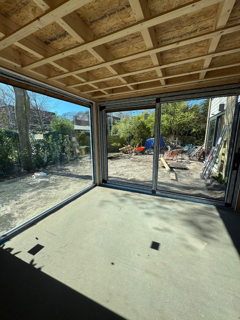 Uitbouw in aanbouw met grote glaspartijen